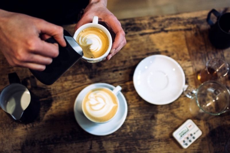 flatlay of man pouring milk into latte, How much does it cost to live in Portland Oregon pins (2)